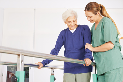Physiotherapeutin hilft einer alten Seniorin auf einem Laufband bei der Physiotherapie